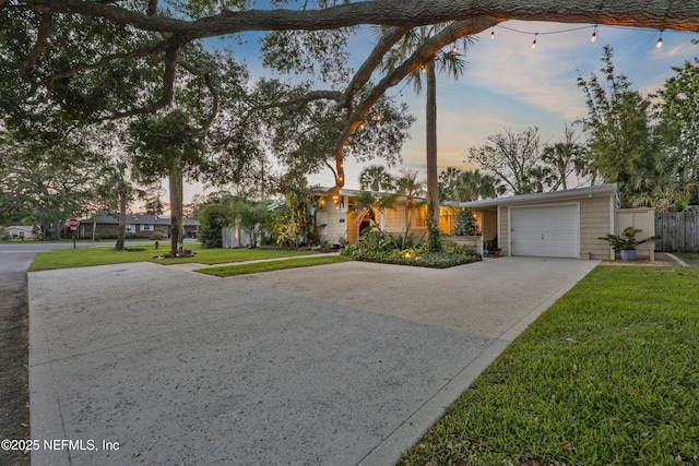 view of front of house featuring a lawn, fence, driveway, and a garage