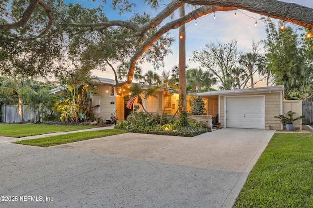 ranch-style home with a garage, fence, driveway, and a front lawn