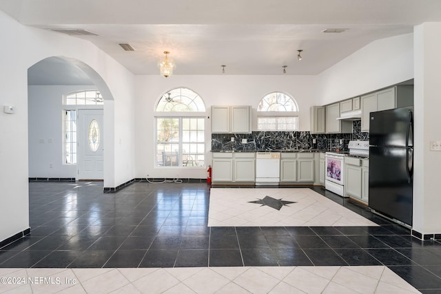 kitchen with dark tile patterned flooring, tasteful backsplash, and white appliances