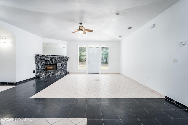 unfurnished living room with ceiling fan, dark tile patterned flooring, a premium fireplace, and vaulted ceiling