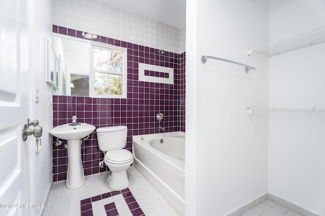 bathroom with toilet, a washtub, tile patterned floors, sink, and tile walls