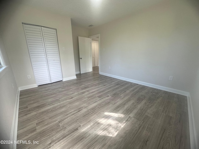 unfurnished bedroom featuring a closet, hardwood / wood-style floors, and a textured ceiling