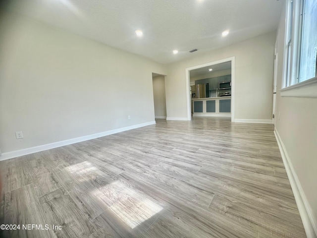 unfurnished living room featuring light wood-type flooring and a textured ceiling