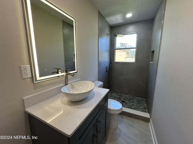 bathroom with walk in shower, vanity, toilet, and a textured ceiling