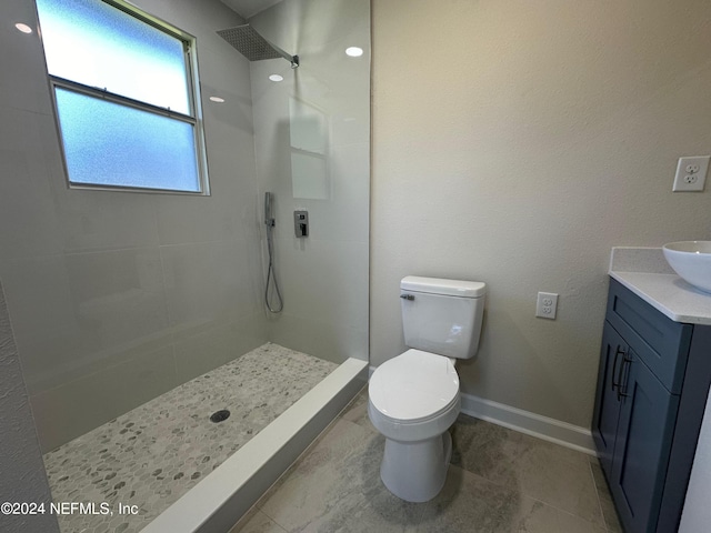 bathroom featuring a tile shower, vanity, and toilet