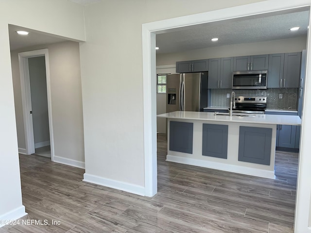 kitchen featuring stainless steel appliances, hardwood / wood-style floors, a kitchen island with sink, and sink