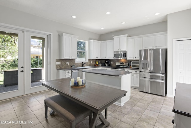 kitchen featuring a healthy amount of sunlight, decorative backsplash, appliances with stainless steel finishes, and white cabinetry