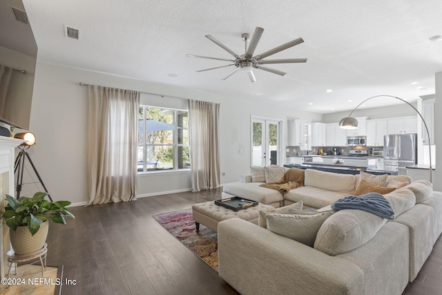 living room featuring ceiling fan, a textured ceiling, and dark hardwood / wood-style flooring