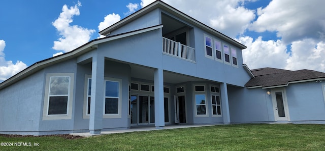 back of property with a balcony and a lawn