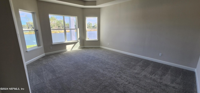 spare room with a water view and carpet