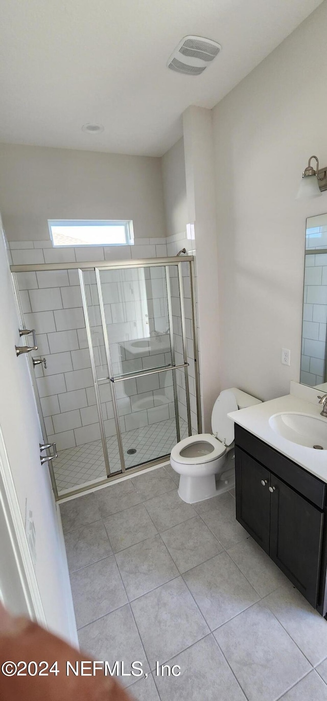 bathroom with an enclosed shower, toilet, tile patterned flooring, and vanity