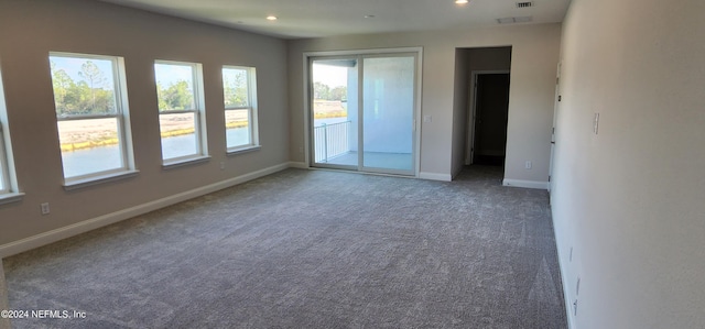 unfurnished room with plenty of natural light and dark colored carpet