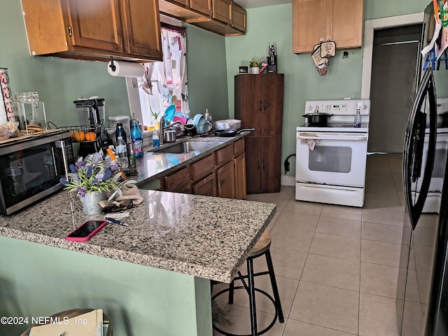 kitchen with light tile patterned flooring, a breakfast bar area, sink, kitchen peninsula, and white electric range oven