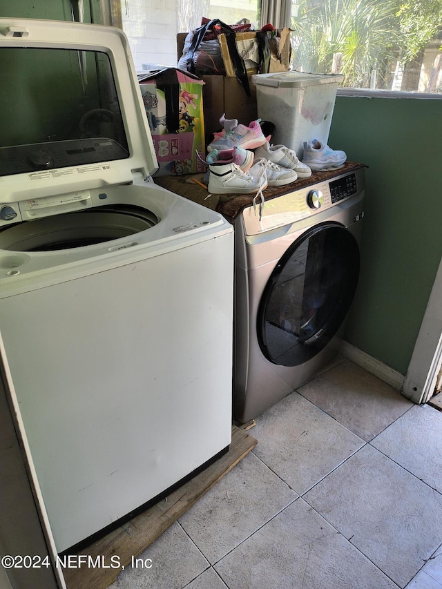 clothes washing area with washer and clothes dryer and light tile patterned floors