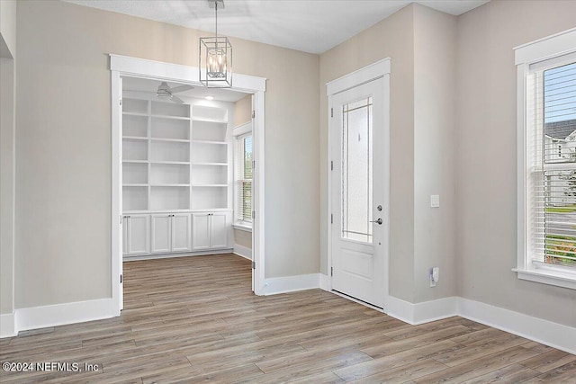 foyer entrance featuring light wood-type flooring, a wealth of natural light, and a chandelier