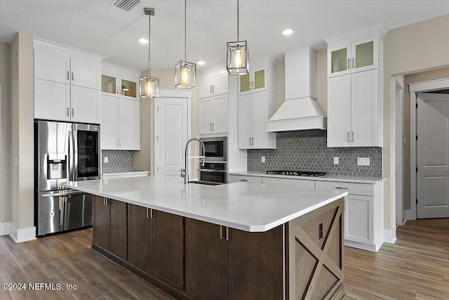 kitchen with custom exhaust hood, white cabinetry, a large island, and appliances with stainless steel finishes