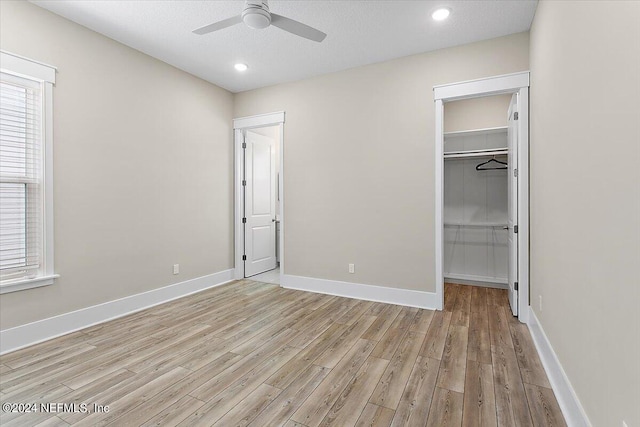 unfurnished bedroom with light wood-type flooring, ceiling fan, a closet, and multiple windows