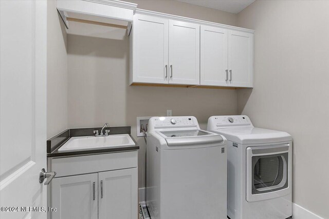 clothes washing area with sink, cabinets, and washer and clothes dryer