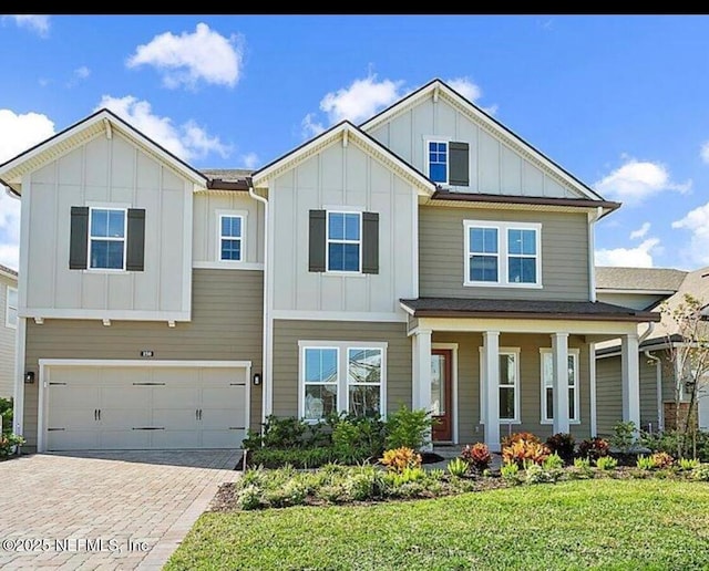 craftsman inspired home with a porch, a front lawn, and a garage