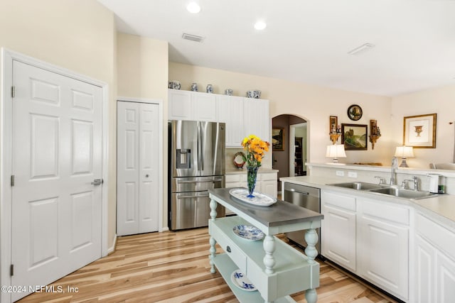 kitchen featuring appliances with stainless steel finishes, white cabinets, sink, and light wood-type flooring