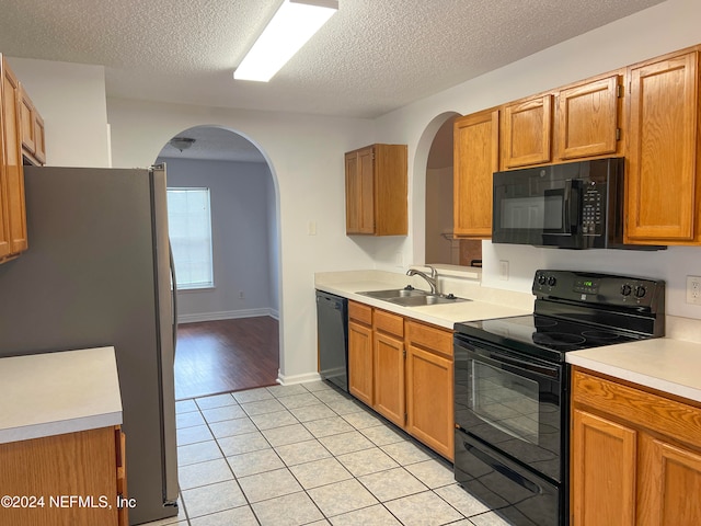 kitchen featuring light hardwood / wood-style floors, a textured ceiling, black appliances, and sink