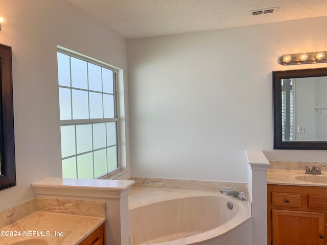 bathroom with vanity, a textured ceiling, and a tub