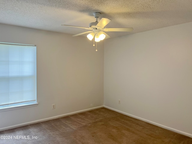 spare room featuring dark colored carpet, a textured ceiling, and ceiling fan