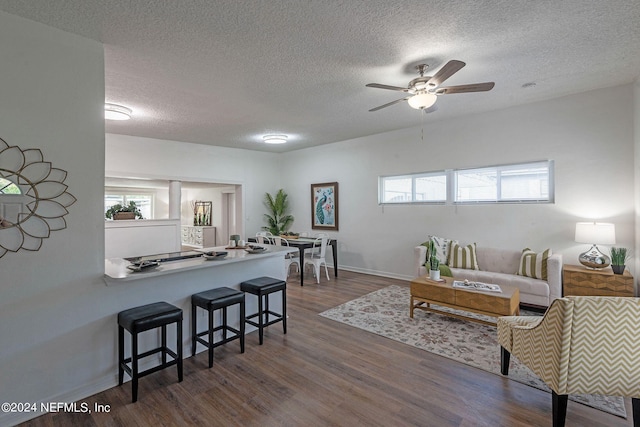 living room featuring a textured ceiling, dark wood-type flooring, and ceiling fan