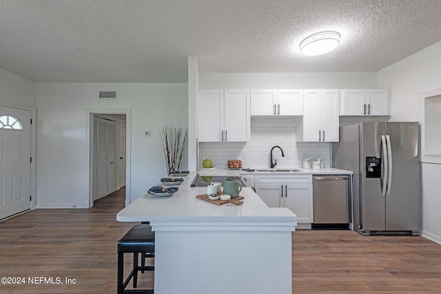 kitchen featuring appliances with stainless steel finishes, white cabinetry, hardwood / wood-style flooring, a textured ceiling, and sink