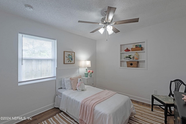 bedroom with ceiling fan, wood-type flooring, and a textured ceiling