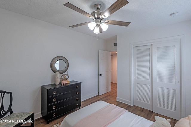 bedroom featuring a closet, a textured ceiling, dark wood-type flooring, and ceiling fan