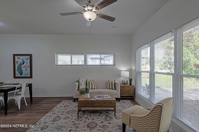 living room featuring a textured ceiling, dark wood-type flooring, plenty of natural light, and ceiling fan