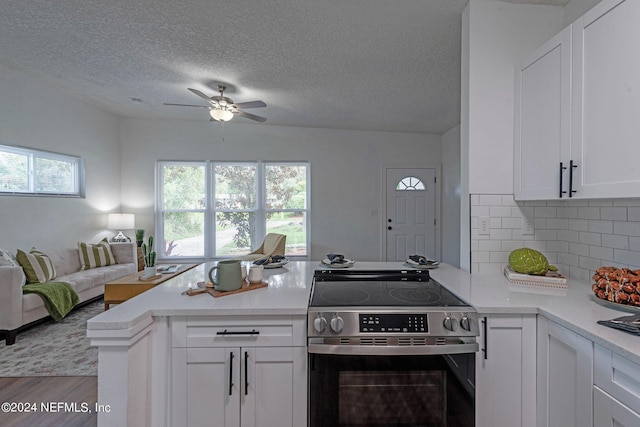 kitchen with light hardwood / wood-style floors, kitchen peninsula, white cabinetry, and stainless steel range with electric cooktop