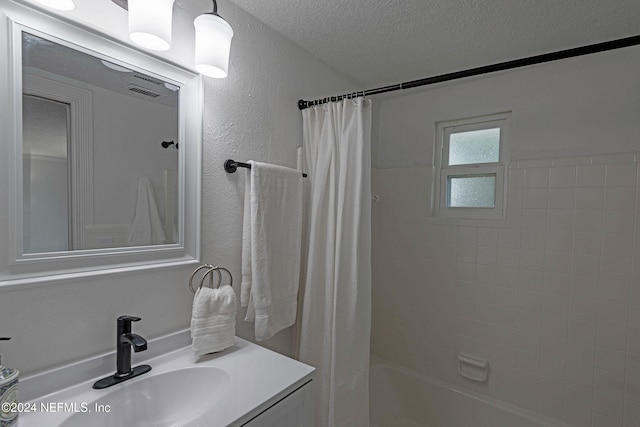 bathroom with vanity, a textured ceiling, and shower / bathtub combination with curtain