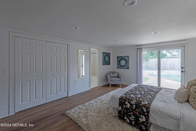 bedroom with a closet, a textured ceiling, wood-type flooring, and access to exterior