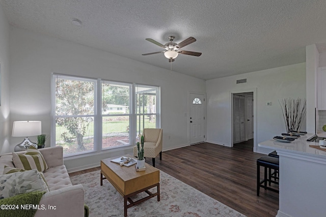 living room featuring a wealth of natural light, a textured ceiling, dark hardwood / wood-style floors, and ceiling fan