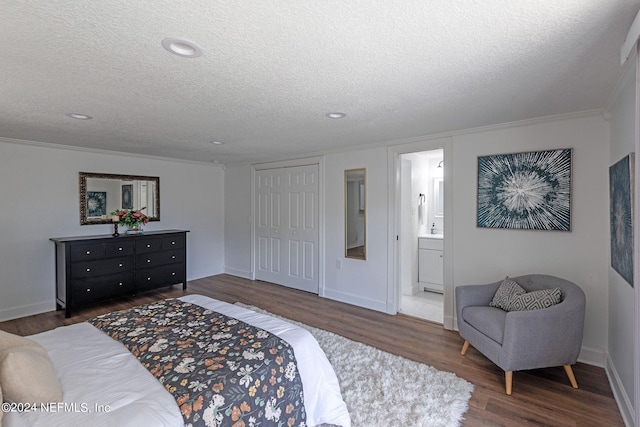 bedroom featuring dark hardwood / wood-style flooring, a textured ceiling, ornamental molding, a closet, and ensuite bath