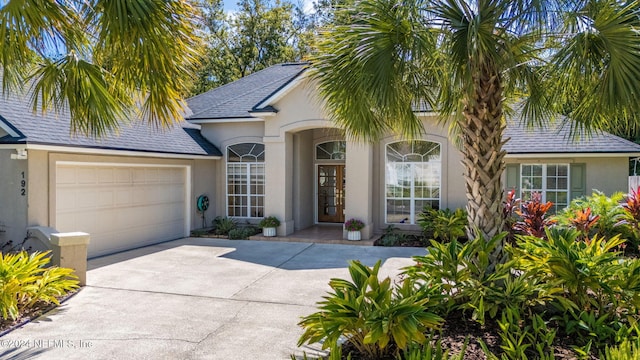 view of front facade featuring concrete driveway, an attached garage, and stucco siding