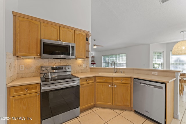 kitchen with stainless steel appliances, light countertops, decorative backsplash, a sink, and a peninsula