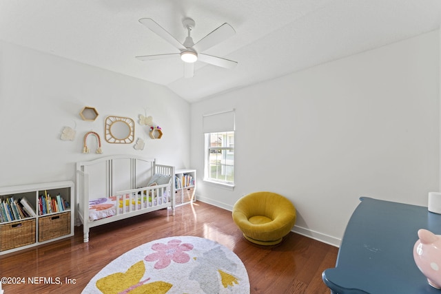 bedroom with a crib, baseboards, a ceiling fan, wood finished floors, and vaulted ceiling