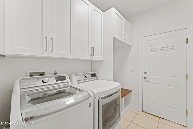 washroom featuring cabinet space, washing machine and dryer, and light tile patterned floors