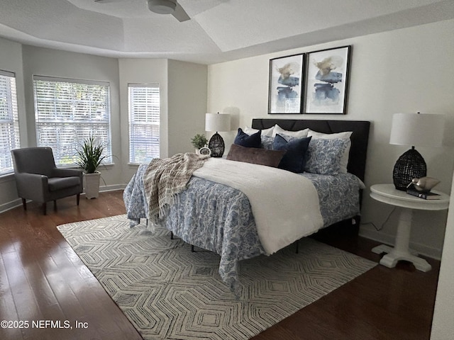 bedroom featuring a tray ceiling, wood finished floors, and baseboards