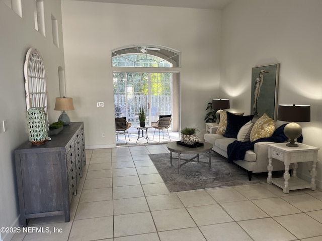 living room featuring a towering ceiling, baseboards, and light tile patterned floors