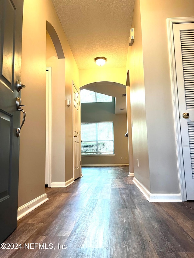 hall with a textured ceiling and dark hardwood / wood-style floors