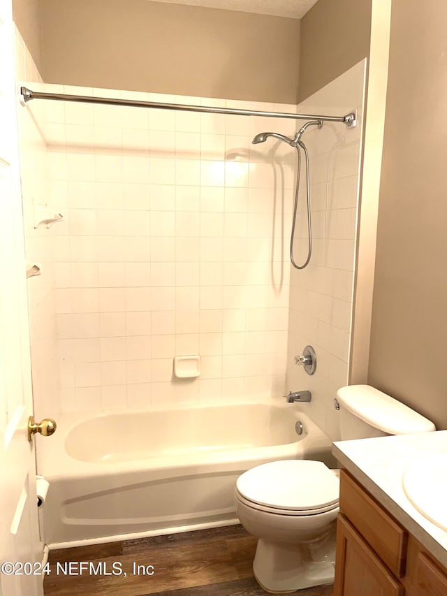 full bathroom with tiled shower / bath combo, vanity, hardwood / wood-style flooring, and toilet