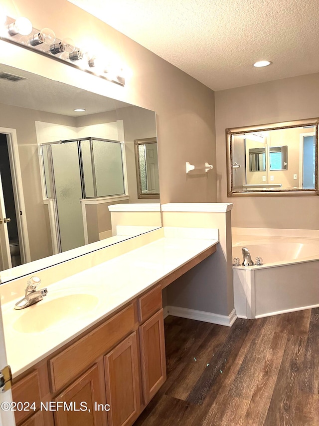 bathroom with a textured ceiling, vanity, hardwood / wood-style flooring, and separate shower and tub