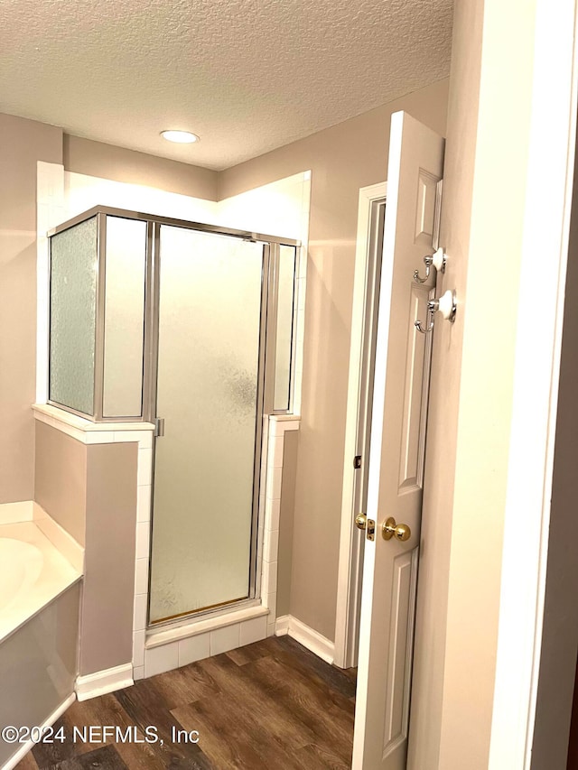 bathroom with hardwood / wood-style floors, a textured ceiling, and separate shower and tub