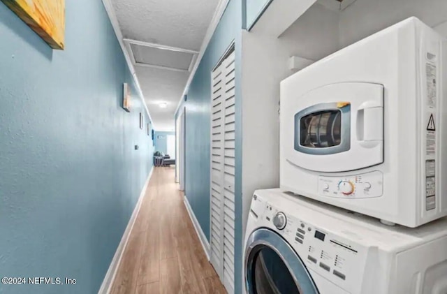 clothes washing area with stacked washer and clothes dryer and hardwood / wood-style flooring