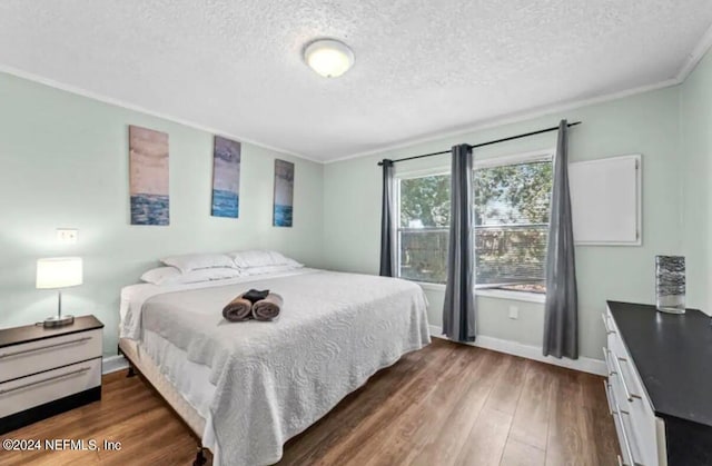 bedroom featuring a textured ceiling, crown molding, and dark wood-type flooring