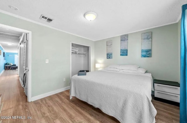 bedroom featuring ornamental molding, a closet, hardwood / wood-style floors, and washer / clothes dryer